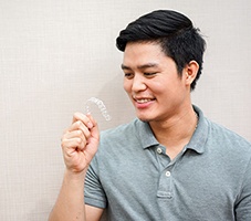 Man in blue polo looking at clear aligner while holding it