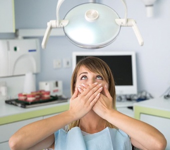 A woman covering her mouth in the dental chair.