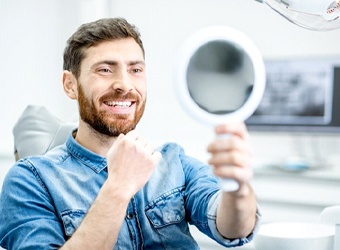 dental patient admiring his reflection after getting tooth-colored fillings in Falmouth