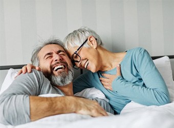 a woman with dentures laughing with her husband