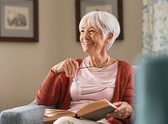 a woman at home smiling with her new dentures