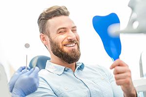Man admiring his new smile after cosmetic dentistry in Falmouth