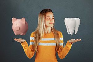 Woman holding piggy bank and tooth representing cost of cosmetic dentistry in Falmouth