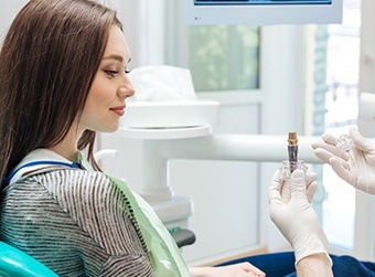 Woman looking at dental implant model