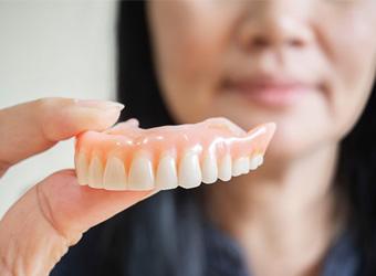 a person holding their dentures