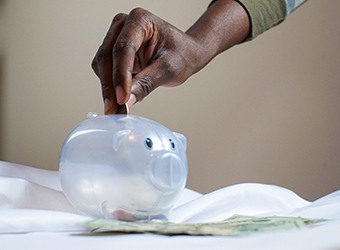 Hand putting coin in piggy bank