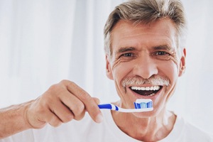 Smiling man brushing his dental implants in Falmouth