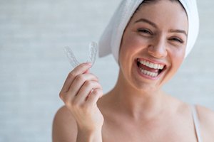 Woman holding mouthguard for protecting her dental implants in Falmouth