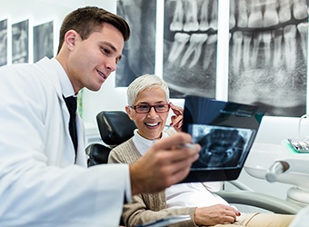 Smiling woman reviewing X-ray with dentist