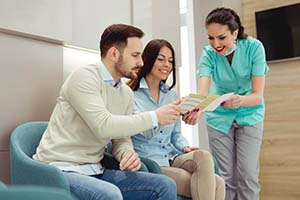 dental team member showing paperwork to two patients