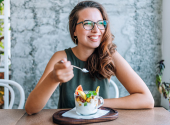 Woman with glasses smiling while eating snack