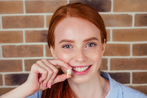 Girl holding up tooth next to mouth
