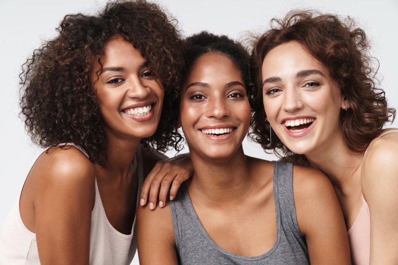 Three women smiling and showing their teeth