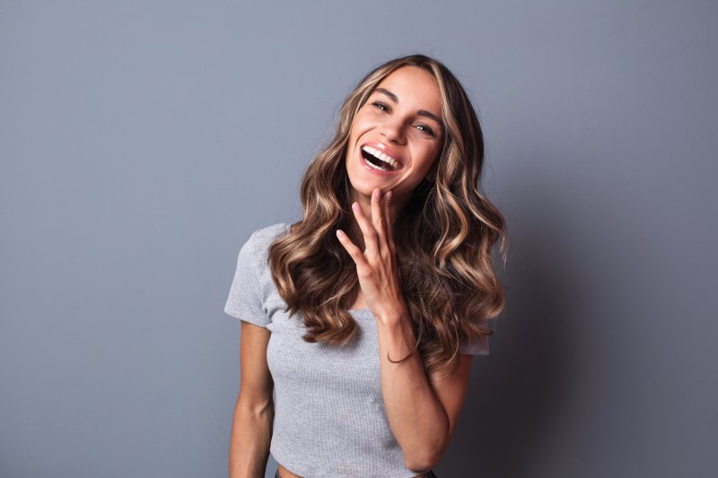 Woman smiling with metal crown replacement