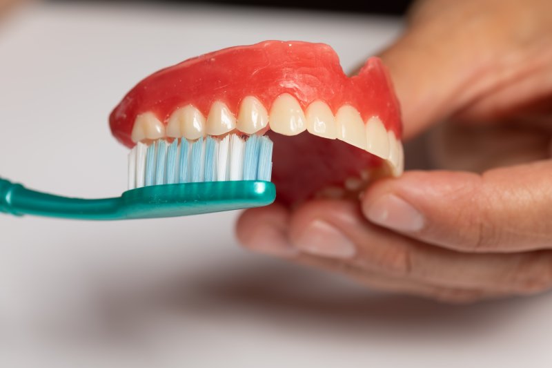 Falmouth patient cleaning dentures with toothbrush