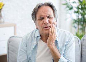 Man rubbing one side of mouth due to jaw pain
