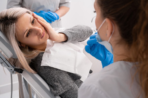 Woman with toothache looking up at emergency dentist