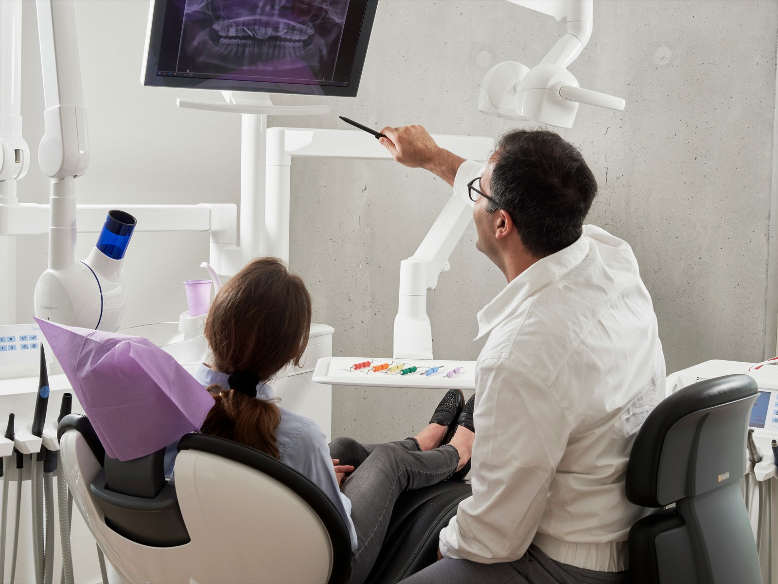 Dentist reviewing a panoramic dental X-ray on screen with a patient in the treatment chair