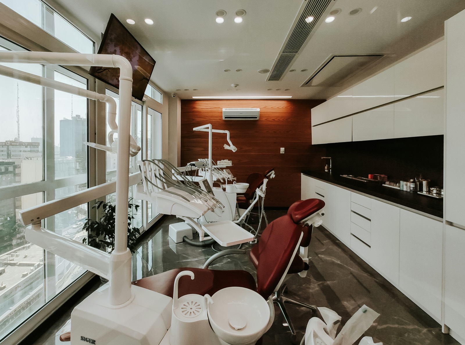 Modern dental operatory with reclining treatment chairs beside floor-to-ceiling windows
